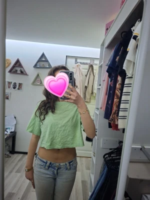 Ljusgrön croppad topp - Säljer en ljusgrön croppad topp med korta ärmar. Toppen har en avslappnad passform och är tillverkad i ett tunt, mjukt material som känns skönt mot huden. Perfekt för varma dagar och enkel att styla med jeans eller kjol. Sitter tyvär ingen lapp i men skulle gissa på kanske typ storlek S.