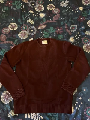 Stickad tröja - Vinröd stickad tröja i merinoull från Colorful Standard köpt på CareofCarls hemsida för ca 1200 nypris. Storlek xs passar även s. Några småhål som uppkommit men inte något som direkt sticker ut (se bilder). Skriv vid funderingar!