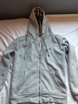 Grå zip hoodie från Burberry - Säljer en grå zip hoodie från Burberry. Perfekt för dig som gillar stilrena plagg med en twist av lyx. Knappt andvänd, inga defekter alls. Hör av er vid funderingar!✌🏼