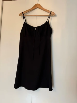 Söt svart klänning - Säljer en svart kort klänning från Gina Tricot i storlek L. Supersöt med en knytdetalj vid bysten som ger den mer karaktär än en vanlig svart klänning. Pris är förhandlingsbart så passa på!!