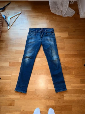 Replay Anbass hyperflex 31/32 - Snygga blå jeans från Replay modell hyperflex anbass.. Klassisk femficksmodell med dragkedja och knapp i midjan. Jeansen har en tvättad look och passar perfekt till en avslappnad stil. 