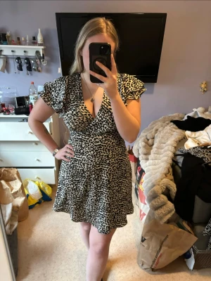 Leopardmönstrad klänning - Säljer nu denna snygga klänning med leopardmönster och v-ringning. Klänningen har dragkedja och så man kan knyta i ryggen för en fin passform 🥰
