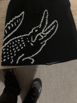 Svart Lacoste mössa  - Säljer en helt ny svart Lacoste mössa man kan även göra den vit 