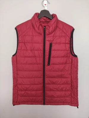 Röd quiltad väst med dragkedja från Zara - Snygg röd väst med quiltat mönster och hög krage. Västen har en svart dragkedja framtill och en bröstficka med dragkedja. Perfekt för lager-på-lager och ger en sportig look. Materialet är lätt och smidigt, vilket gör den enkel att bära. Har två sidofickor och två fickor på insidan. Västen är i fint använt skick, har en  fläck på framsidan som knappt syns och som säkert går bort i tvätten :). Köpt på Zara, storlek L. 
