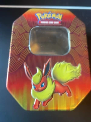 Pokémon samlarburk - Säljer en färgglad samlarburk i metall från Pokémon Trading Card Game med Flareon på locket och Jolteon på sidan. Burken har ett fönster på ovansidan och är perfekt för att förvara kort eller småprylar. Motiv i rött, gult och orange.