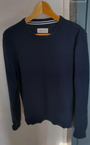 Mörkblå stickad tröja Pier One M - Mörkblå stickad tröja från Pier One med rund halsringning och långa ärmar. Tröjan har en enkel och stilren design med ribbade muddar vid ärmslut och nederkant. Perfekt basplagg för en clean look.