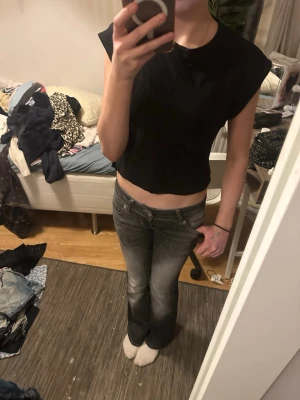 Svart croppad topp från Cubus - En enkel svart croppad topp från Cubus med rund halsringning och ärmlös design. Perfekt till jeans eller kjol för en clean och stilren look. Tillverkad i mjuk bomull som känns skön mot huden.