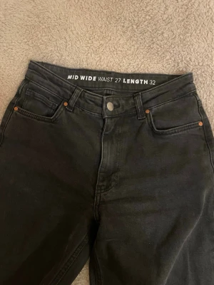 Svarta mid wide jeans bikbok - Säljer ett par svarta jeans mid wide passform och raka ben. Midjan är 27 och längden 32.  Nypris 700
