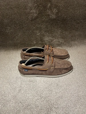 Seglarskor  - Hej! Säljer dessa bruna Dockside loafers från märket Marstrand! Dessa är tillverkade i Portugal och har materialen: nubuck, läder, mocka och gummi! Otroligt härliga loafers som passar perfekt nu till sommaren! Nubucken är i ett mycket gott skick som visas på bild 5! (Nubuck är slipat läder för er som inte vet) som mocka fast mer korthårigt. Storleken är 41. Lite smått slipade vid hälen annars i gott skick utan defekter! Hör gärna av er vid minsta intresse så svarar jag snabbt 😊mvh DS