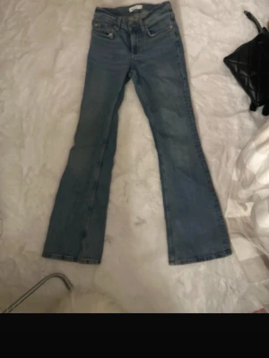 Bootcut jeans från Gina tricot - Säljer ett par midrise bootcut utsvänga blå jeans från Gina tricot. Jeansen har fyra fickor, bälteshällor och en snygg ginatricot-lapp bak i midjan. Perfekta till vardagslooken och tillverkade i slitstark denim.trendiga och snygga. Pris kan diskuteras 