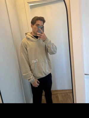 Beige hoodie THE MET tryck - Säljer en beige hoodie från THE MET med stor ficka framtill och huva. På ryggen finns ett stort vitt tryck med texten THE MET. Hoodien har avslappnad passform och är gjord i mjukt bomullsmaterial. Perfekt för en chill och stilren look.
