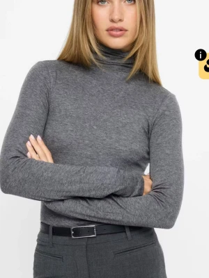 Grå polotröja  - Snygg grå polotröja med lång ärm och tight passform. Tillverkad i en mjuk och stretchig bomullsmix som känns skön mot huden. Perfekt att bära under jackor eller som den är för en clean look.