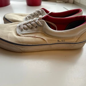Vans sneakers  - Vans Era sneakers i beige canvas med rött foder och läderdetaljer. Använda, men i mycket gott skick! Hör gärna av dig vid fler frågor, önskemål om fler bilder etc. 😊