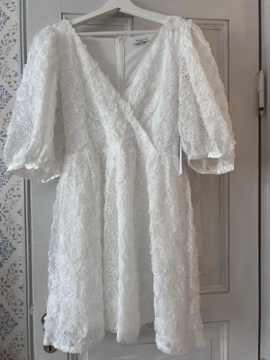 Studentklänning  - Vit blommig klänning som passar perfekt till studenten! Den är köpt för 999kr.