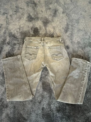  replay - Snygga gråa jeans från replay med klassiska bakfickor med ikonisk söm. Jeansen har bälteshällor och är gjorda i ett slitstarkt denimtyg. Perfekta för en avslappnad och trendig look.