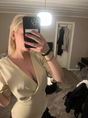 Ljus omlottklänning från Sisters Point - Säljer en ljus omlottklänning från Sisters Point i storlek XS. Klänningen har korta ärmar, v-ringad urringning och markerad midja. Perfekt för dig som gillar stilrena och feminina plagg.