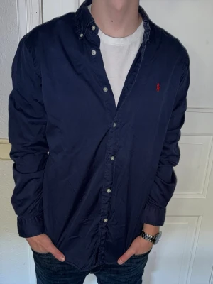 Mörkblå skjorta från Ralph Lauren - Mörkblå skjorta från Ralph Lauren i storlek L. Fint skick till ett bra pris. Nypris: 1995kr. Mitt pris: 349kr. Vid frågor eller funderingar, tveka inte att höra av dig.