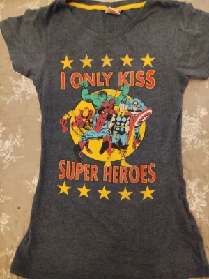 Marvel Comics superhjälte t-shirt - Mörkgrå t-shirt från Marvel Comics med tryck av flera superhjältar och texten 'I ONLY KISS SUPER HEROES'. T-shirten har korta ärmar, rund hals och färgglatt motiv med stjärnor. Perfekt för dig som älskar Marvel och vill sticka ut.300kr postar med postnord vid intresse pm 🩵🩵🩵
