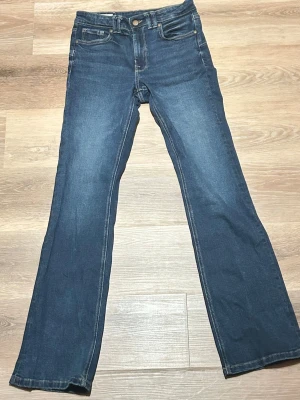 Mörkblå bootcut jeans från zara - Snygga mörkblå bootcut jeans med klassisk femficksdesign och kontrastsömmar. Jeansen har normal midja och är tillverkade i stretchigt denimtyg för extra komfort. Perfekta för en avslappnad och trendig look.