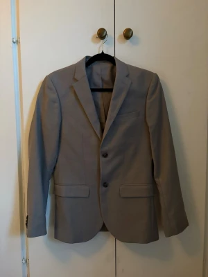 Grå kavaj - Stilren beige kavaj med två knappar framtill och klassisk krage. 