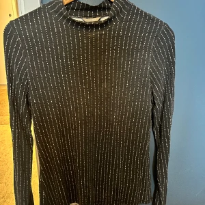 Grå/vitprickig polotröja strl M - Grå/vitprickig polotröja i lyocell och viskos. Fint skick förutom ett par skav/slitningar i tyget. Jag upplever dock att detta knappt syns vid användning. Storlek M. 