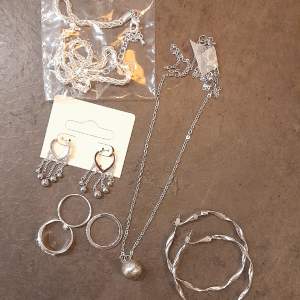 Set med silverfärgade smycken i nyskick Två halsband  Två par örhängen  Tre ringar Estimerat värde: 400kr