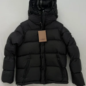 BURBERY JACKA STORLEK M - Helt ny Burrberry jacka, aldrig använd på grund av att den är för liten.  Väldigt varm jacka med avtagbara ärmar, ska att den går att göra om till väst. 