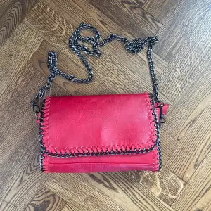 Röd väska med kedja, vet ej märke men köpte den i affär ny och har används några ggr. Finns små defekter, skriv privat för bilder. Bredd 26cm höjd 16cm