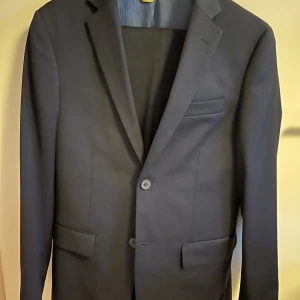 Kostym 44 slim fit  - En kostym som endast är använd fåtal gånger och därför i nyskick. Den är dessutom precis hämtad från kemtvätten. Storlek 44 short slim fit. Modellen på bilden är cirka 168cm.