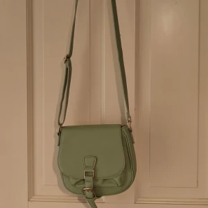 Mintgrön axelbandsväska  - Köpt secondhand men i fint skick, har knappt använt den Justerbart band Litet fack på framsidan samt ett på insidan av väskan. Stängs med hjälp av en knapp