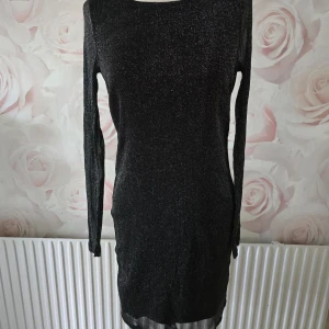 Glittring kort klänning. - Finns en tåd som sticker ut på ena ärmen. Kan inte se något annat att anmärka på.