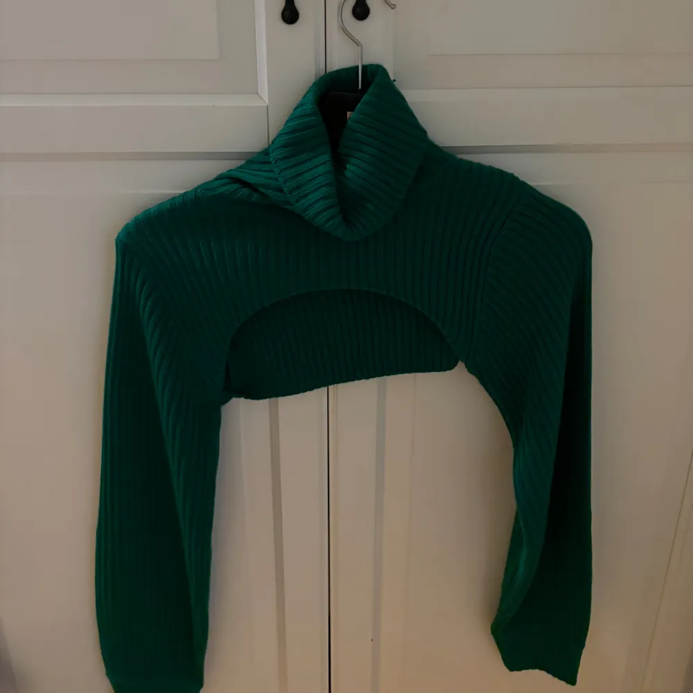 En grön skickad tröja som slutar över bröstet. Väldigt skön krage. Storlek XS. Väldigt fin att ha till ett svart eller vitt linne.. Stickat.
