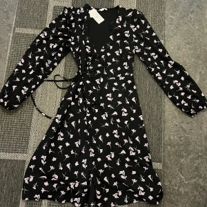 Klänning  - Fin oanvänd klänning med långa armar och rosa detaljer. Aldrig använd och prislappen finns kvar på 