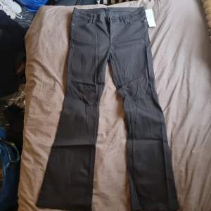 Ett par svarta jeans byxor som har inte blivit använt nån enda gång och har prislappen kvar.