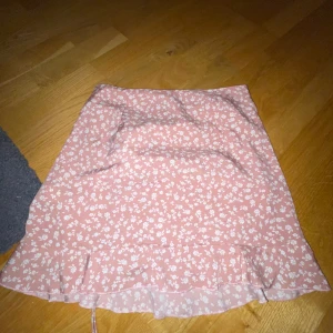 Kjol - Säljer min dammrosa kjol från Shein med små vita blommor på, köpt för 100kr säljer för 65kr för den aldrig kommit till användning, lite liten i sin storlek!!