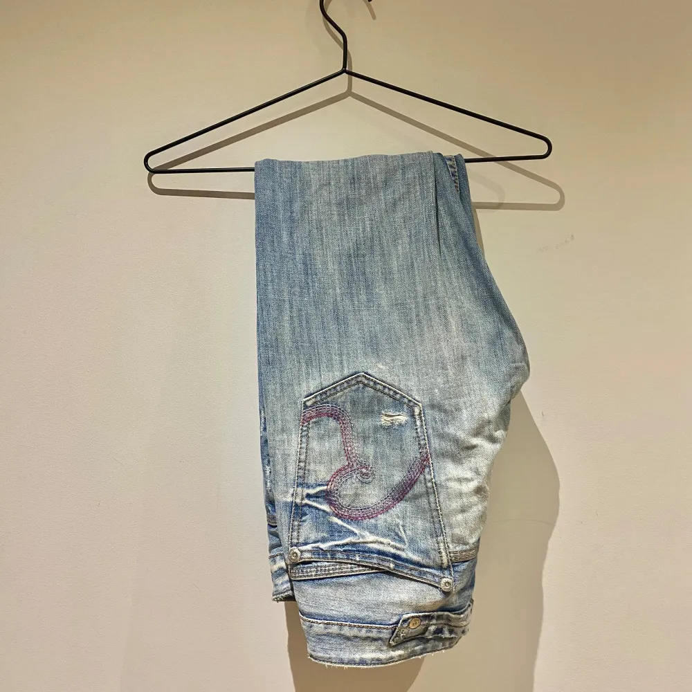 Ett par ljusblå Replay jeans i storlek 29/34. Byxorna har en klassisk femficksdesign med broderade detaljer på bakfickorna. De är tillverkade i denim och har en knapp- och dragkedjestängning.. Jeans & Byxor.