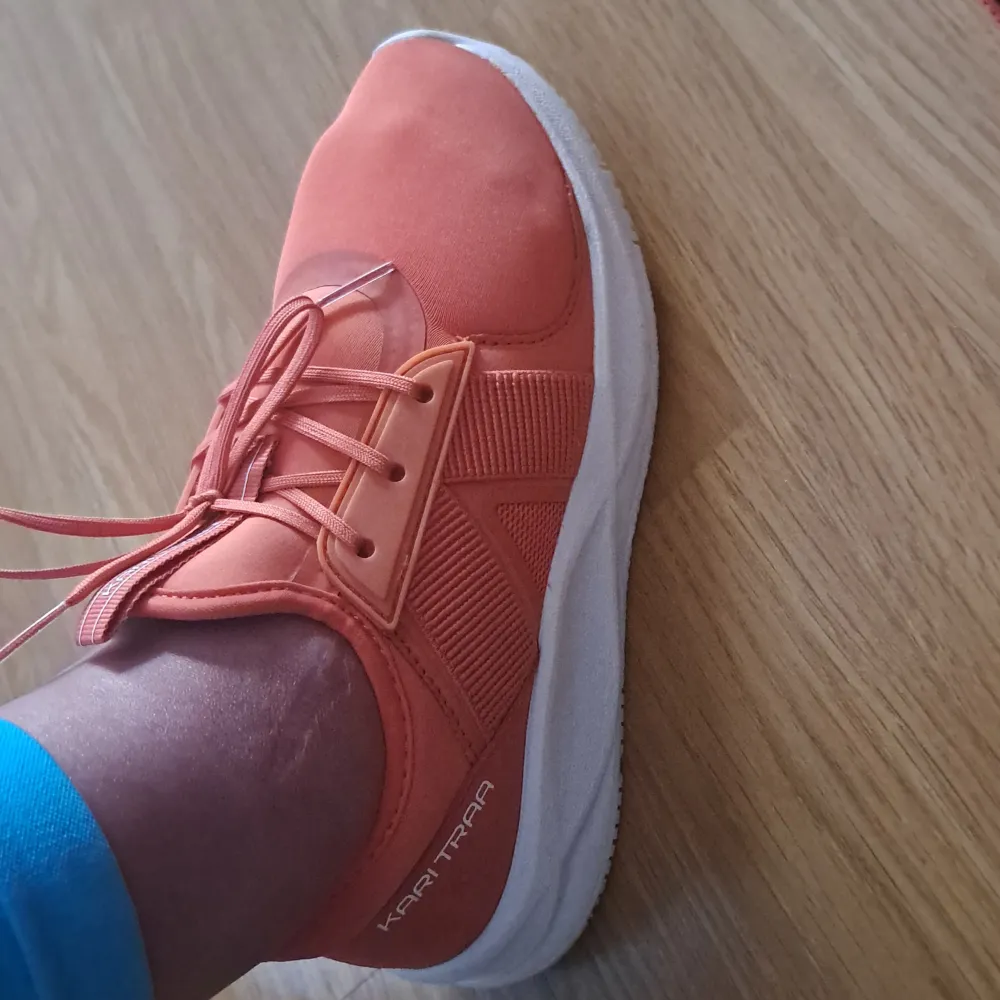 Ett par orange (coral) sneakers från Kari Traa med snörning och vit sula. Skorna har en sportig design och är bekväma för vardagsbruk. storlek 36. Från stadium. Och bär 1 gång bara. . Skor.