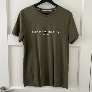 Militärgrön Tommy Hilfiger T-shirt - Superfin t-shirt från Tommy Hilfiger i fin militärgrön färg. Storlek S herr. Helt oanvänd men saknar lapp, i perfekt nyskick!