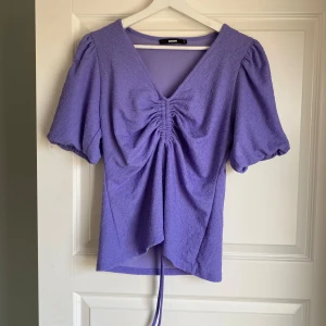 Lila topp - Lila topp från gina tricot, endast prövad. Köpt för ca 250/300 kr. Storlek L men passar även M. Snöret går att dra åt och därav kan v-ringningen ”justeras”. 