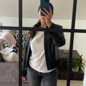Svart skinnjacka - Säljer denna super fina svarta skinnjacka i äkta skinn ifrån Hollister! Den har mörkgröna muddar och är super fin! Tyvärr för liten på mig:/ 