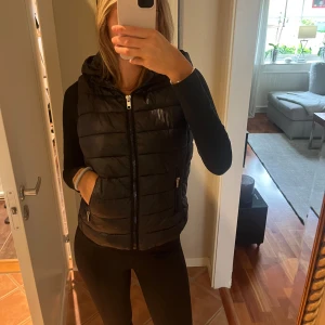 Väst  - En svart väst från Mango. Storlek Xs men passar mig med som brukar ha S. Luvan går att ta bort! 