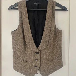 Väst - Brun-ish väst med guldglitter, köpt second hand i vint skick! Saknar tredje knappen 