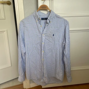 Ralph Lauren - rutig skjorta - Vit och blå rutig skjorta från Ralph Lauren. Storlek: M. Skick: 9/10. Nypris: runt 2000kr. Kontakta oss för fler bilder eller info!🙌