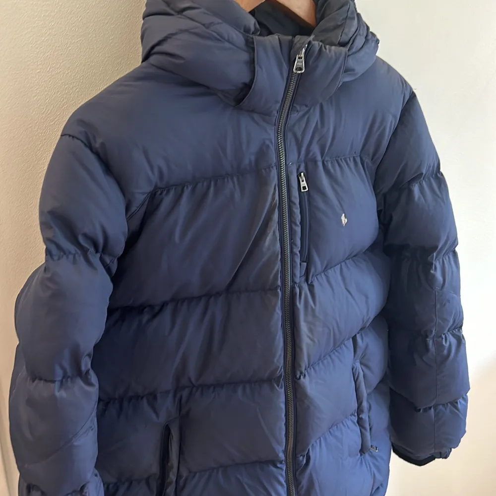 Snygg tidslös Ralph Lauren dunjacka i stl 164. Mörkblå. Lite sliten i trycket och i behov av en tvätt ! Enfärgad. Min son hade den när han var 13-15 år och han är normalväxt. . Jackor.