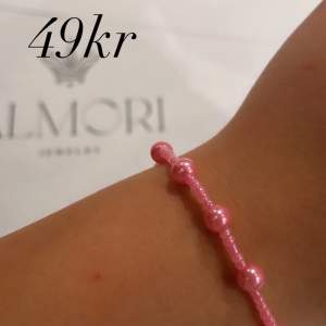 Ett rosa pärlarmband från Almori. Armbandet består av små rosa pärlor och är enkelt och elegant i designen.