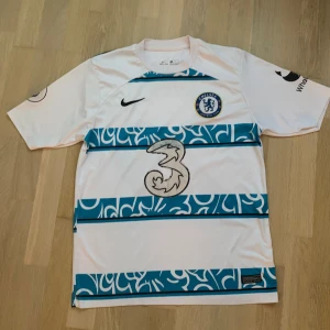 Chelsea bortatröja 22/23 Havertz 29 - Chelsea fc fotbollströja från säsongen 22/23 med Kai Havertz 29 där bak. Tröjan är i bra skick förutom att trycket har gått loss lite i tvätten. Den är storlek S men passar M
