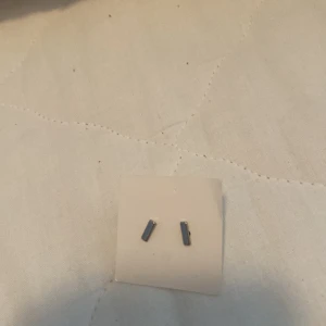 Svarta örhängen - Ett par små, rektangulära svarta örhängen.