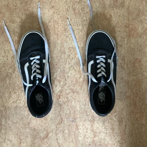 Svarta Vans sneakers - säljer mina gamla vans pågrund av att jag växte ur dom. använd typ 3 gånger.                          ett par svarta Vans sneakers med vita detaljer och snörning. Skorna har en vit sula med det klassiska rutmönstret på undersidan och en röd 'Off the Wall' logotyp på hälen. säljer mina gamla vans pågrund av att jag växte ur dom. använd typ 3 gånger.