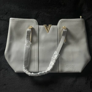 Grå handväska  - Grå skinn väska . Den har en ficka på baksidan med dragkedja samt två fickor på insidan med dragkedja. Köpt utomlands🩶