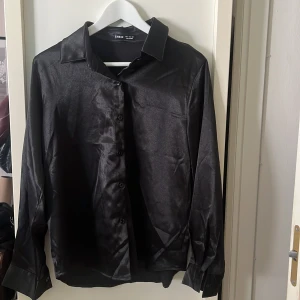 Silkesskjorta i svart - Silkesliknande skjorta i färgen svart, från Shein. I storlek 34/US 2/XS